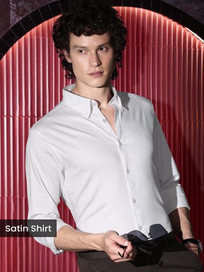 White Satin Shirt Man in a white satin shirts holding sunglasses, posing against a red background.