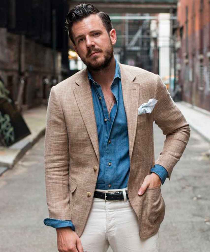 Man model in brown jacket, aqua shirt and blue trousers at white brick wall  Stock Photo | Adobe Stock