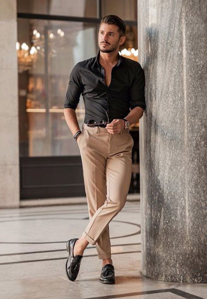 an Asian man in a black shirt and brown pants standing proudly in front of  an old building 28769689 Stock Photo at Vecteezy